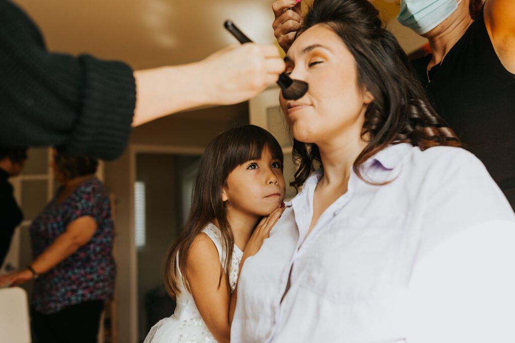 Kimberly's daughter looking at her mom getting her makeup done