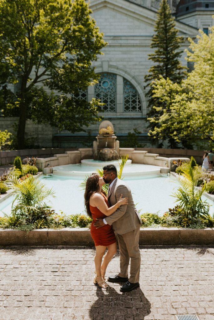 they are kissing in front of the fountain of the oratory